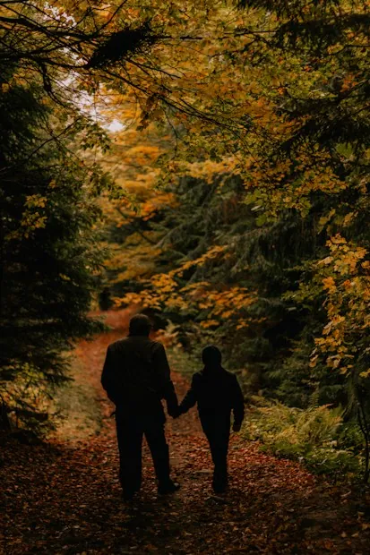 Two people walking along an autumn forest path
